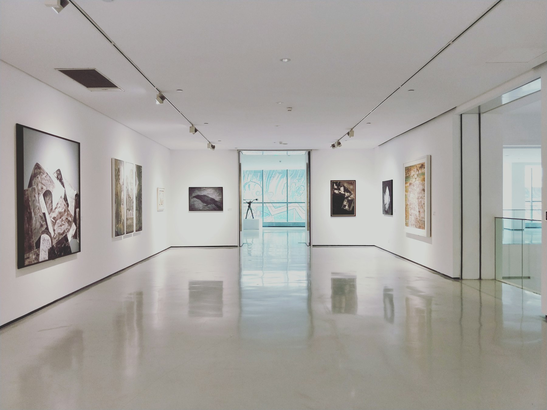 Galerie blanche aux murs ponctués de photographies encadrées