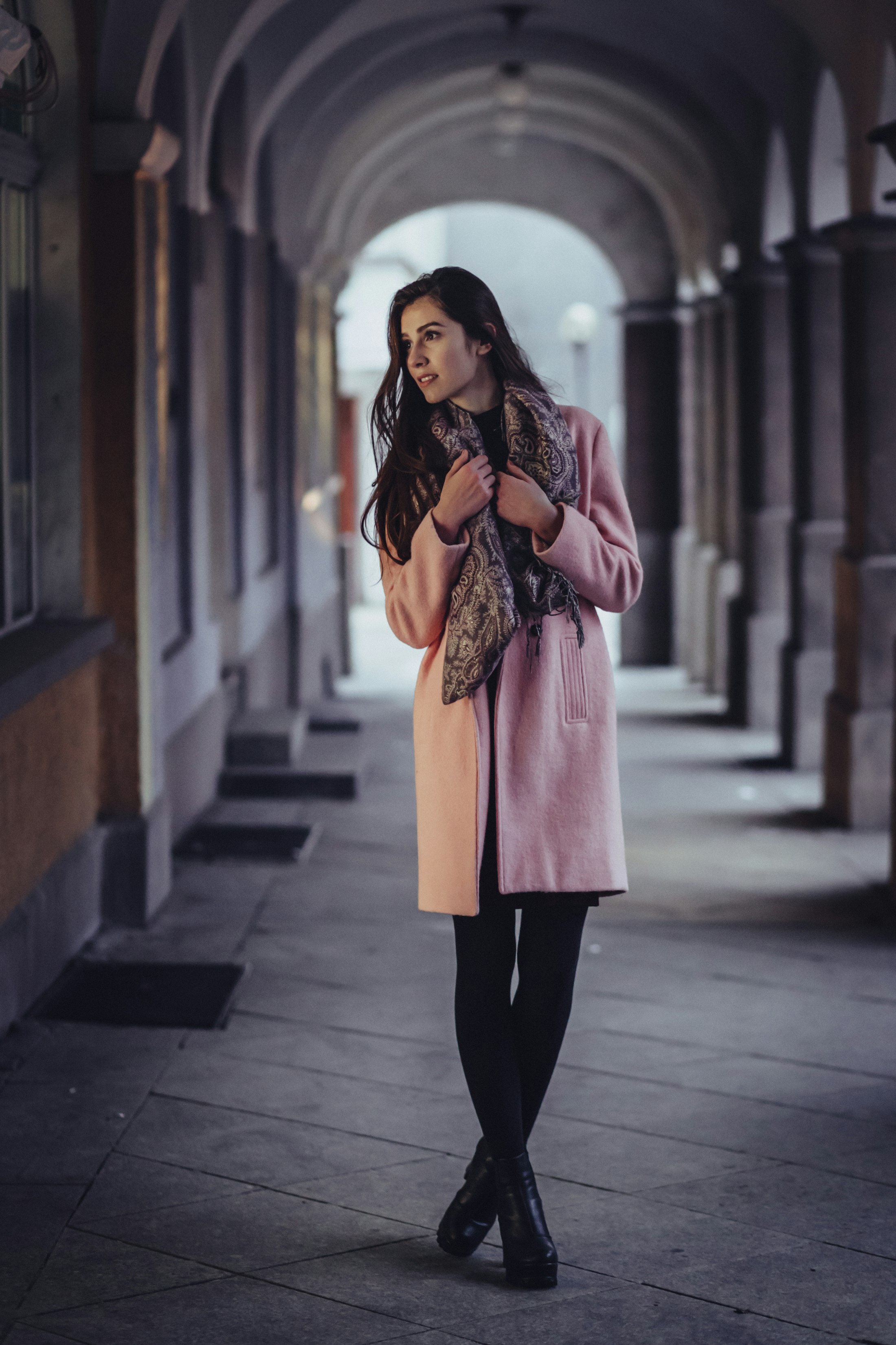 Silhouette en manteau rose sous des arcades
