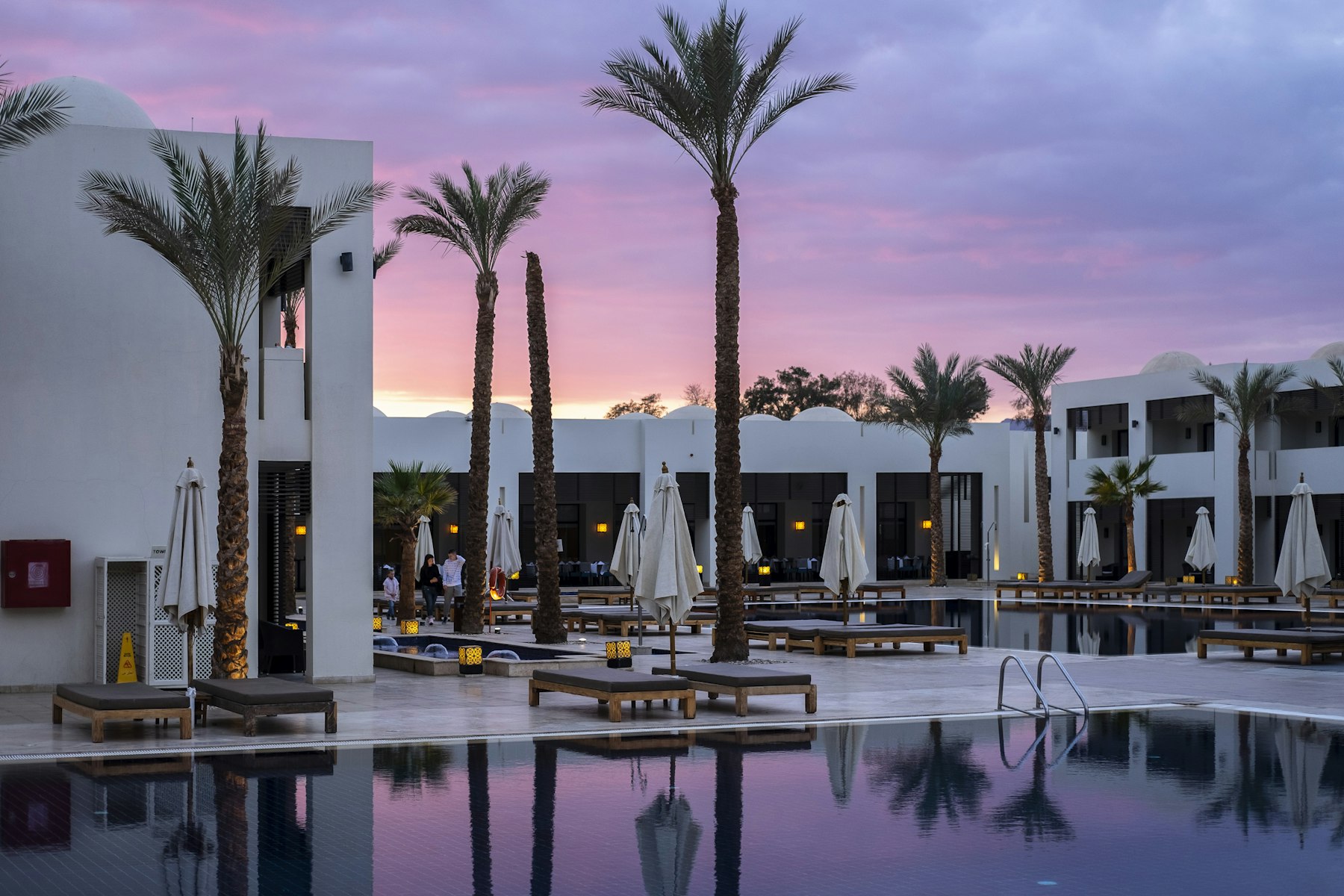 Piscine d'hôtel bordée de palmiers au crépuscule