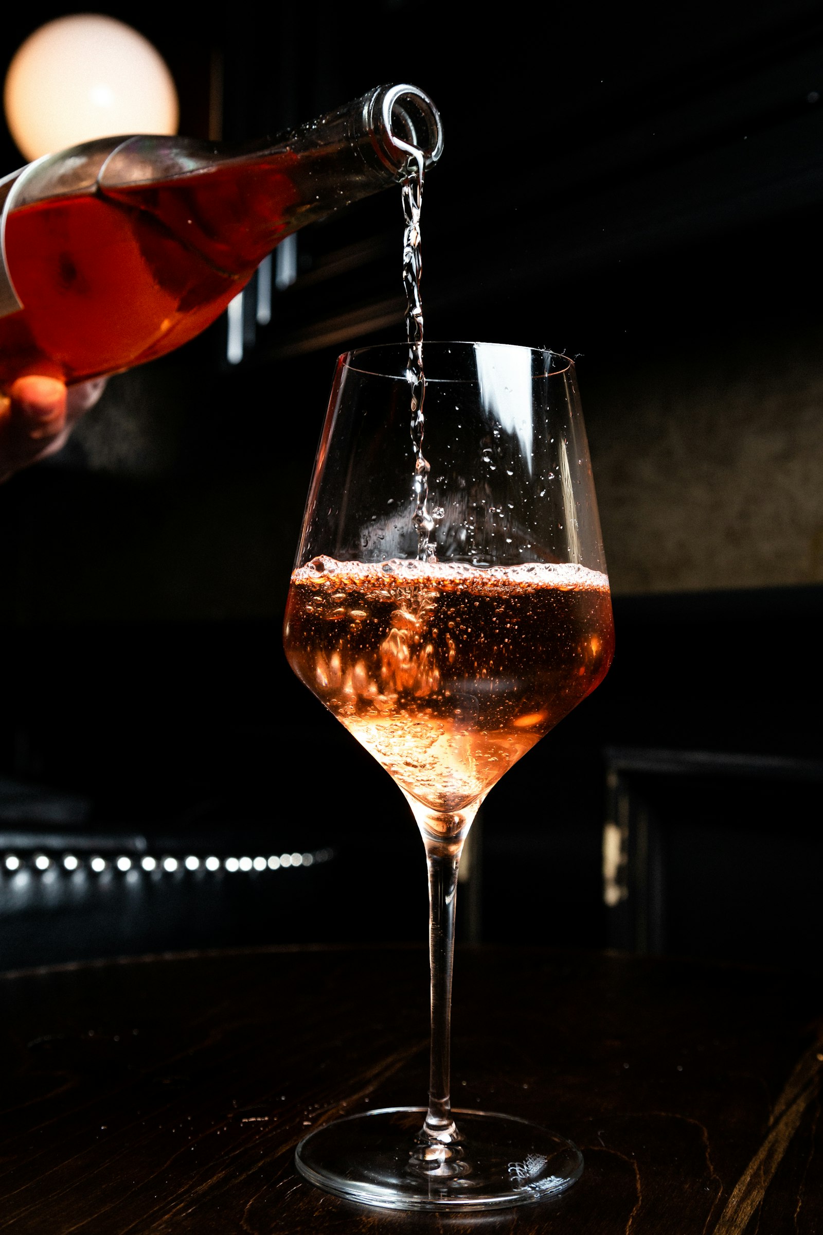 Vin rosé versé dans un verre à pied sur fond sombre